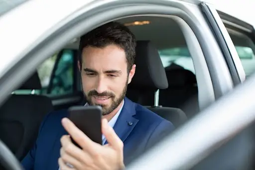 young businessman text in car