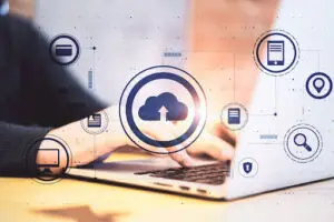 A person types on a laptop keyboard, with cloud computing and digital data icons overlaid, symbolizing cloud storage, data sharing, and digital communication concepts.