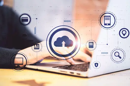 A person types on a laptop keyboard, with cloud computing and digital data icons overlaid, symbolizing cloud storage, data sharing, and digital communication concepts.